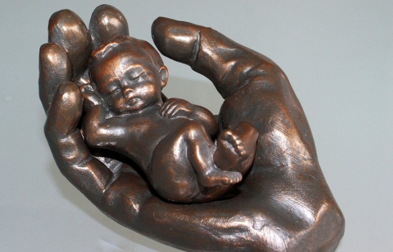 Brons - en hand med ett nyfött barn i.